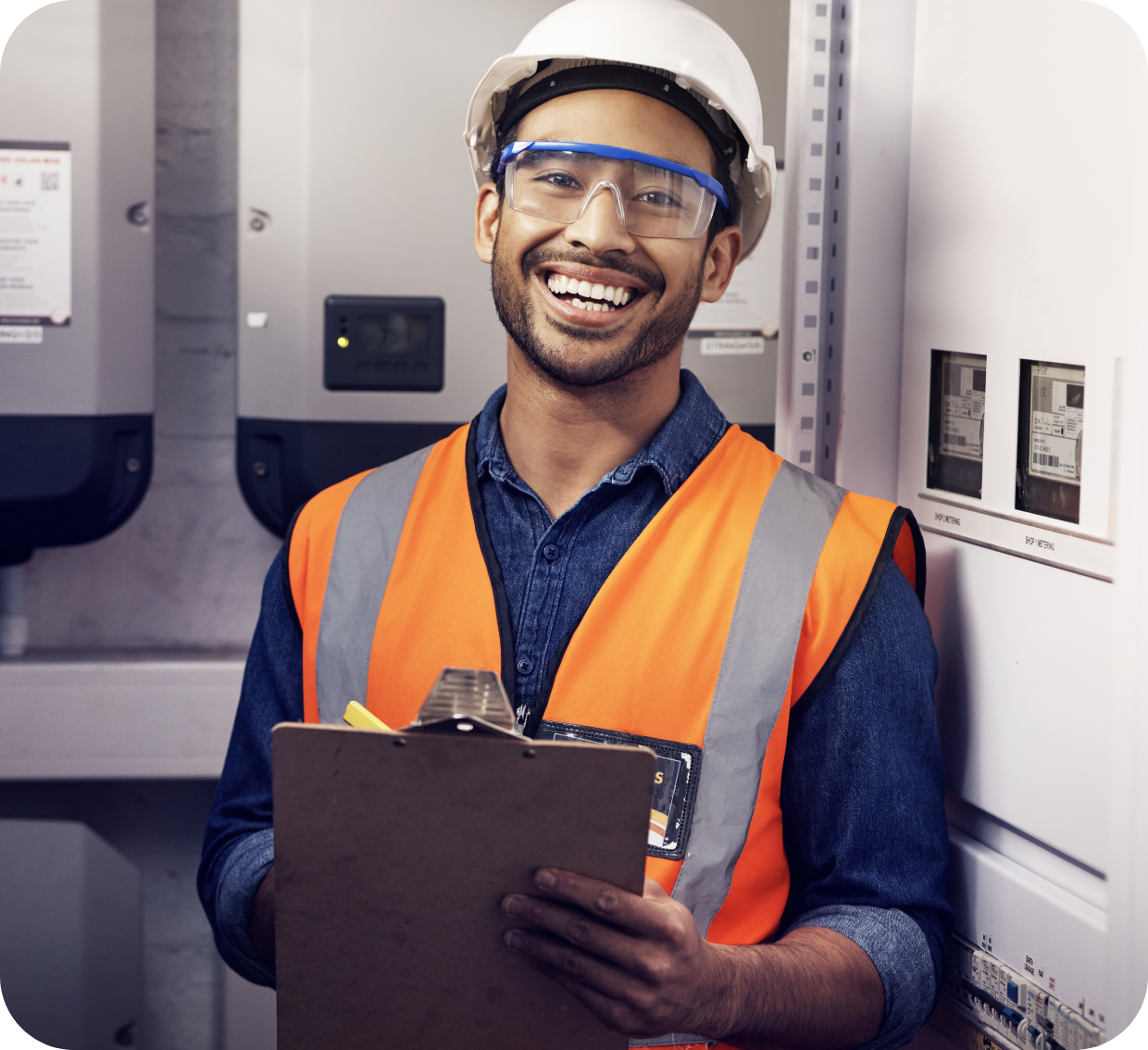 Smiling electrician holding clipboard, safety gear.