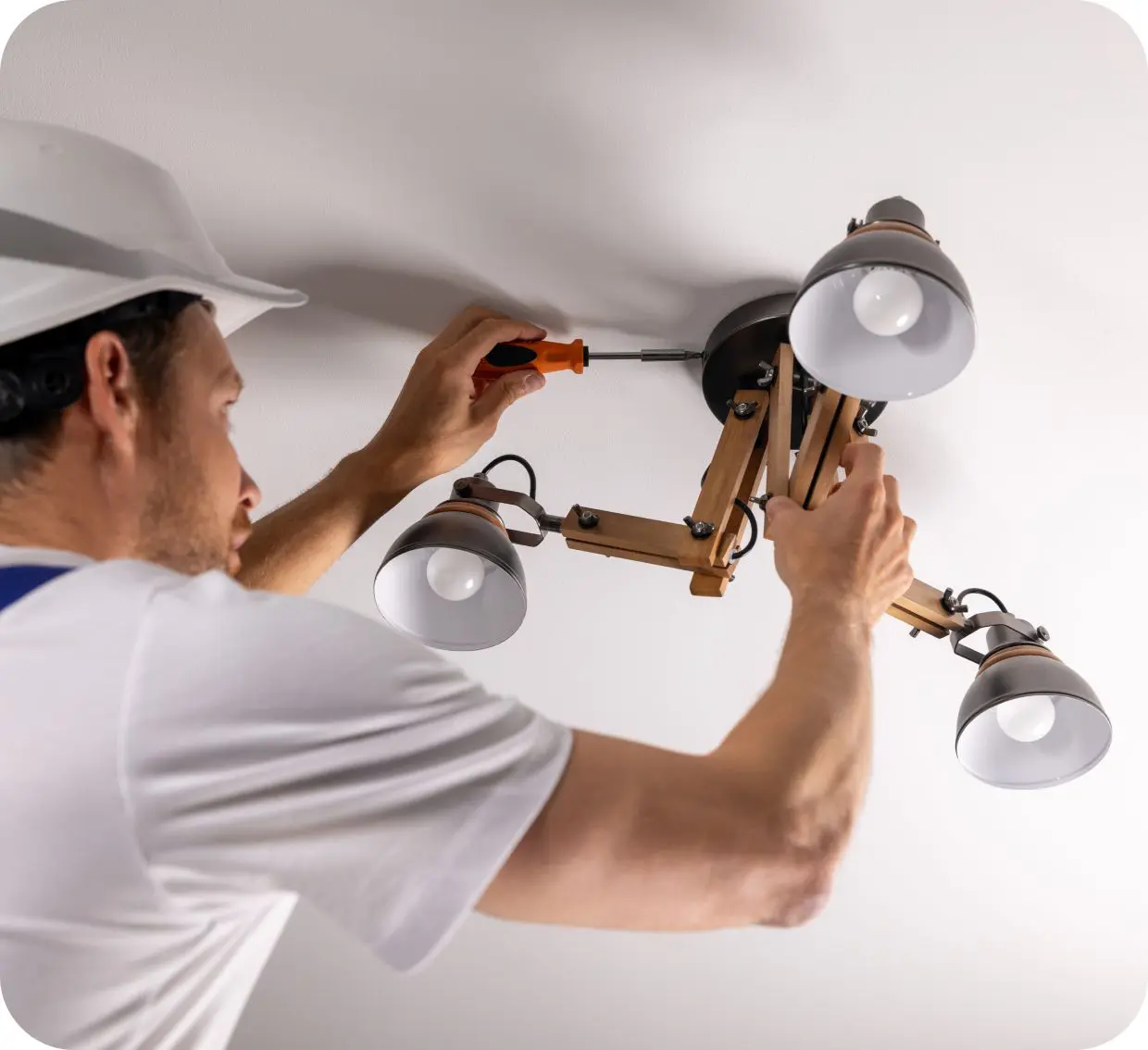 Electrician installing a ceiling light fixture.